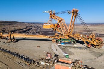 Aerial view of a giant excavator at work in a vast open-pit mining landscape.